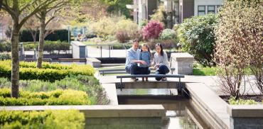 A family walks near a water feature in Wesbrook Place