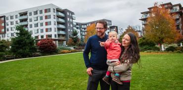 Selfy, her husband, and her toddler standing on the grass looking at one direction
